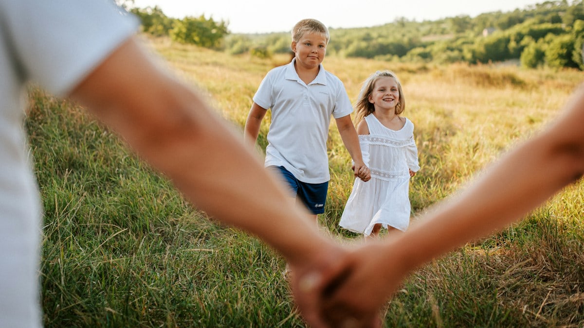 A couple of people holding hands in a field